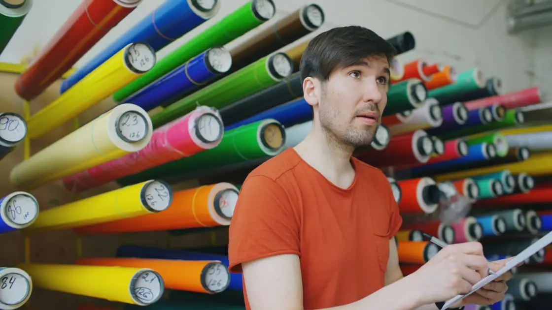 Man checking a wall of coloured vinyl rolls